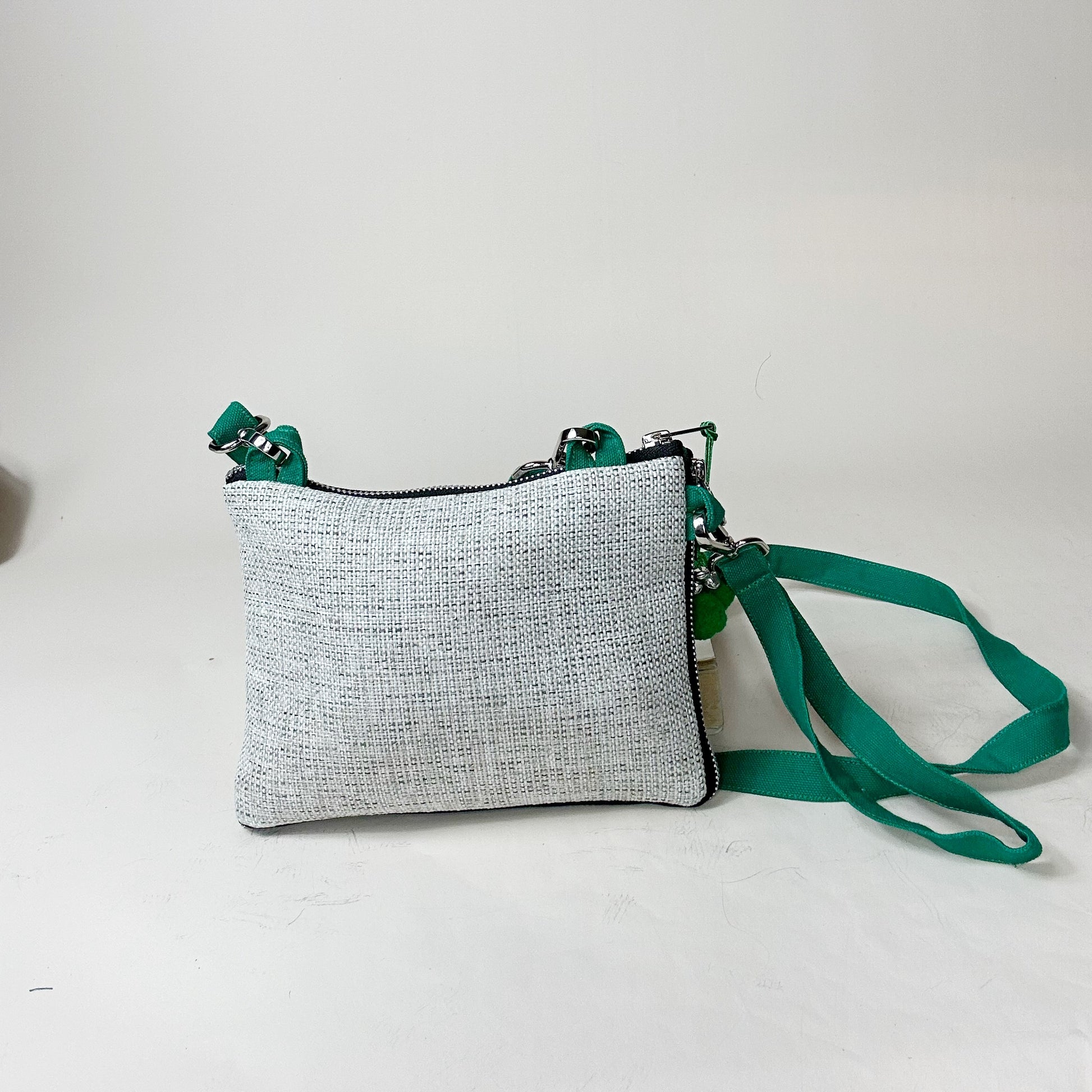 Gray textured crossbody bag with a green strap on a light gray background