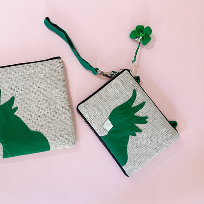 jute cockatoo crossbody bag in green flatlay next to clutch