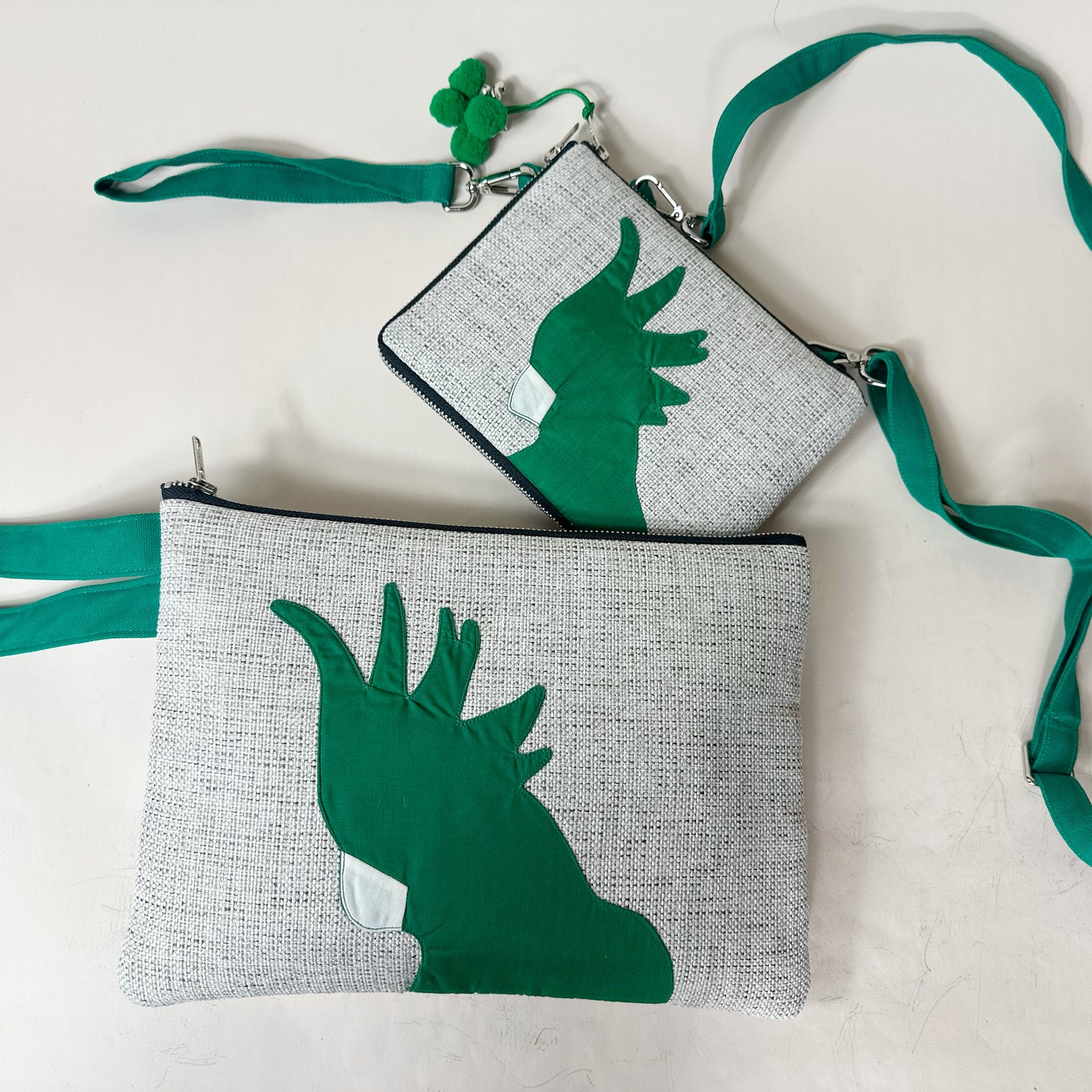 Two gray pouches with green hand designs on a white background